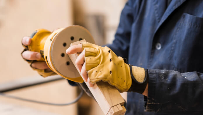 close up male carpenter sanding wooden block with sander 2